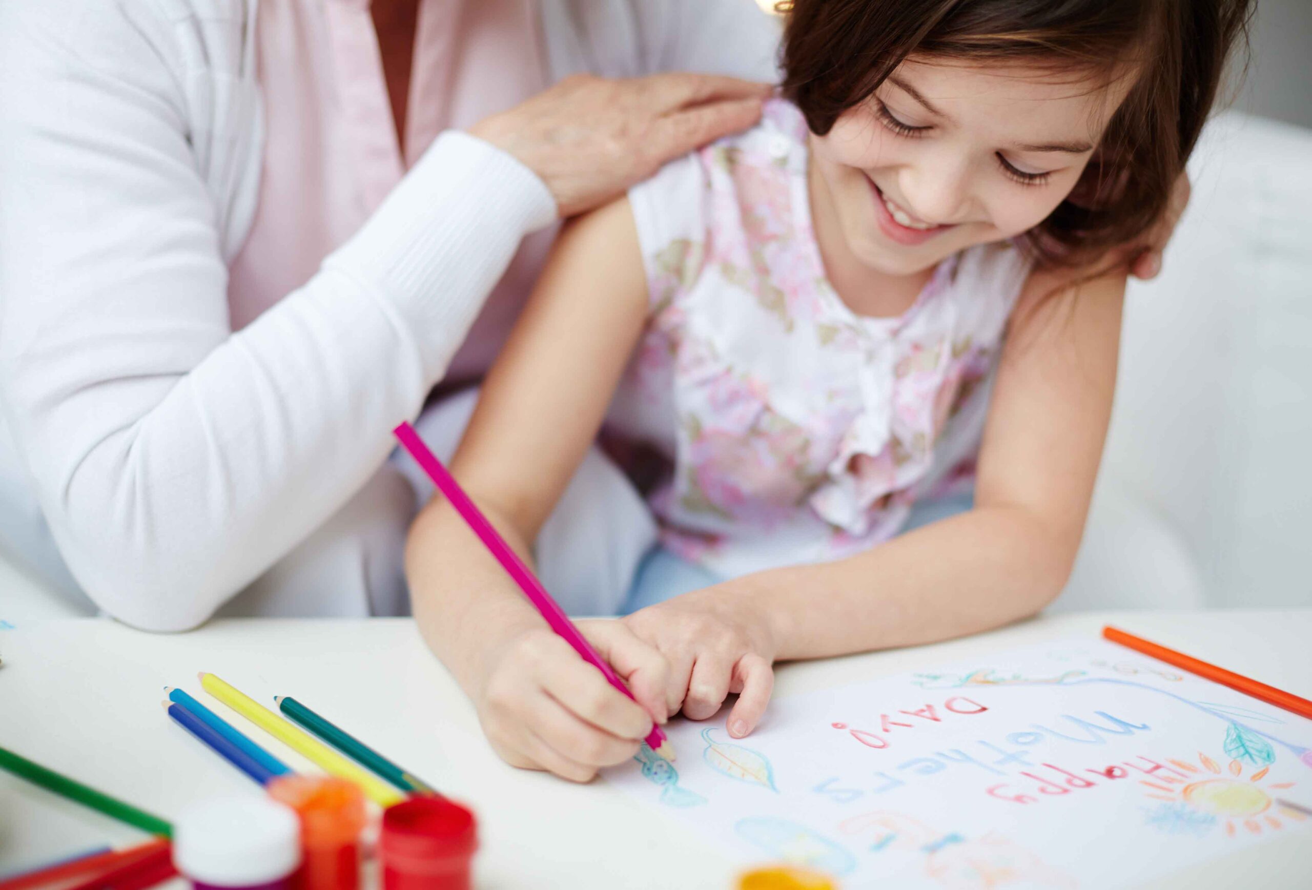 A kid is doing some coloring on a piece of paper as guided by her kindergarten teacher who had graduated in the degree of early childhood education in Malaysia.